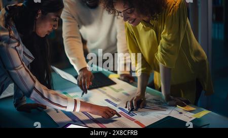 Diverse Creative Colleagues Discussing a New Business Opportunity, Talking in an Office Meeting Room in the Evening. Using Laptop Computer with Project Planning and Development Timeline. Stock Photo
