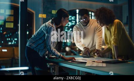 Group of Young Successful Businesspeople Making a Team Meeting in Conference Room in Creative Agency. Excited Diverse Team Using Laptop Computer, Discussing a New Corporate Strategy. Stock Photo