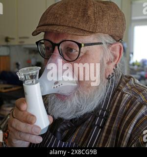 Senior man using a nebulizer to cure throat problems. Stock Photo