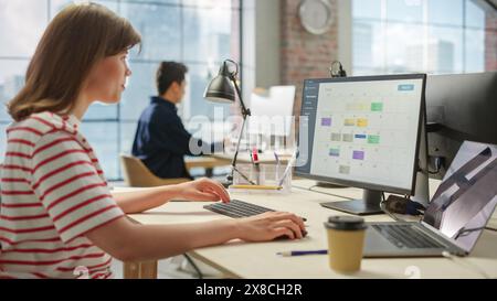 Portrait of Caucasian Creative Young Woman Working on a Calender Software on a Desktop Computer in Bright Busy Office. Female Team Lead Smiling Happily While Checking Team Events for the Month. Stock Photo