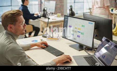 Portrait of Focused Young White Man in Office Working on a Computer Calendar. Male Team Lead Checking Data and Preparing a Schedule. Stock Photo
