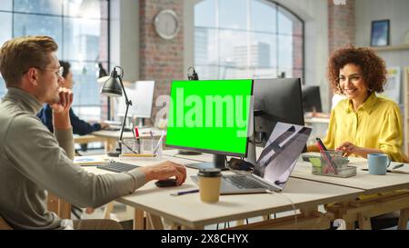 Multiethnic Group of Creative Colleagues Working on Computers in a Modern Bright Office. Male Administrator Preparing a Presentation Using Green Screen. Biracial Businesswoman Smiling. Stock Photo