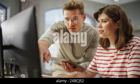 Two Creative Colleagues Collaborating Over a Work Project Using Computer and Tablet. White Male E-commerce Marketing Manager Discussing Plan with White Female Media Planner. Stock Photo