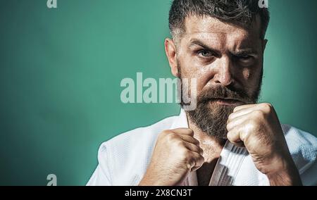 Serious bearded man in kimono in fighting position. Karate fighter preparing for competition. Muscular male ready for karate training. Strong martial Stock Photo
