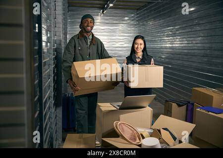 Team of storehouse coworkers posing for camera during cargo unloading Stock Photo