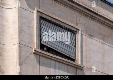 Close-up of a facade with window and weathered, defective, slanted shutter Stock Photo