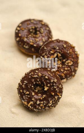 Three chocolate donut with sprinkles on beige background . High quality photo Stock Photo