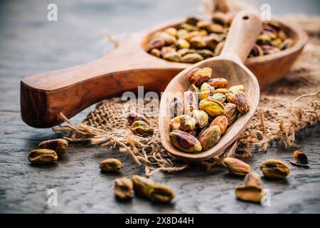 Roasted and peeled pistachios in wooden spoons on wooden background Stock Photo