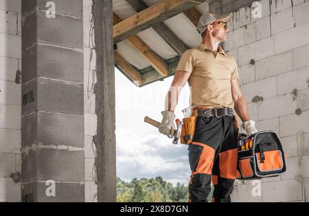 Construction contractor worker standing and holding a tool bag in one hand and a chainsaw in the other. Stock Photo