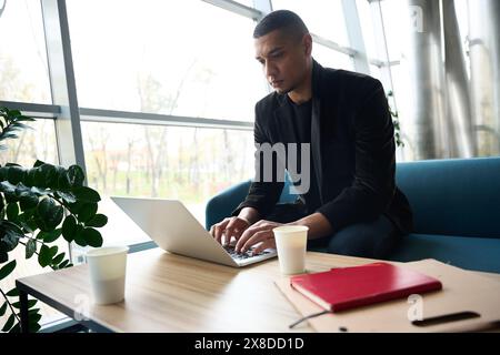 Serious young man sitting at table and typing on laptop Stock Photo