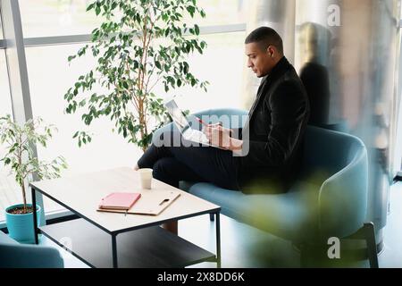 Freelancer sitting while working on laptop and typing on smartphone Stock Photo