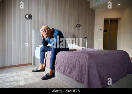Depressed african american male entrepreneur having failure sitting on bed Stock Photo