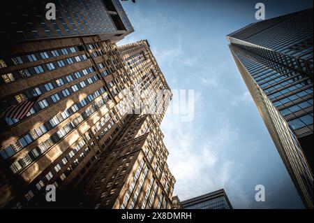 NYC giants reach for the sky! Towering Manhattan buildings dwarf pedestrians on bustling streets. Classic scene for travel and urban life content. Stock Photo