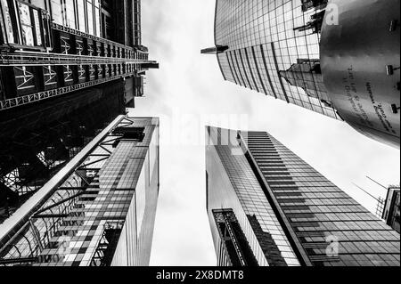 NYC giants reach for the sky! Towering Manhattan buildings dwarf pedestrians on bustling streets. Classic scene for travel and urban life content. Stock Photo