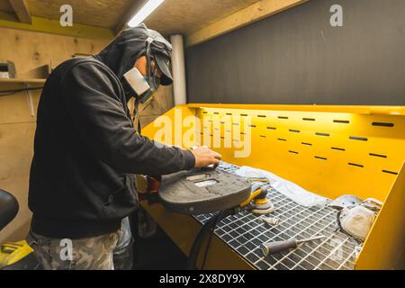 man with mask polishing the guitar, creating a new guitar. High quality photo Stock Photo