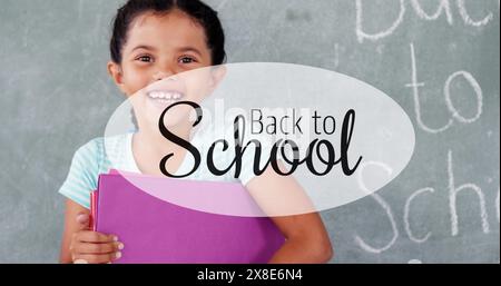 This is a portrait of a smiling schoolgirl holding a file against a chalkboard Stock Photo