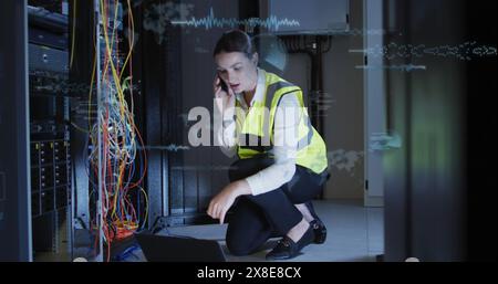 Image of data processing over caucasian female engineer talking on smartphone at server room Stock Photo