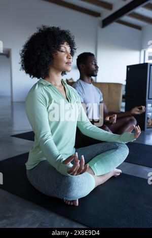 A diverse couple meditating at home, both in casual attire Stock Photo