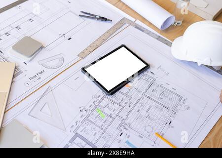 Architectural plans and drawings spread out on table with a tablet in center Stock Photo