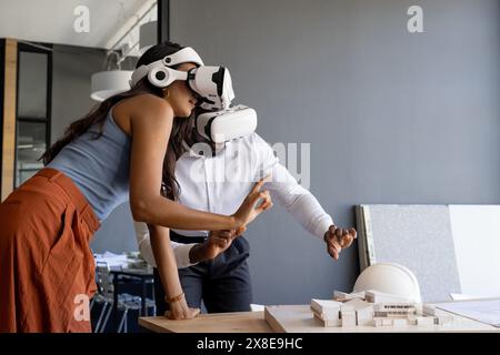 Diverse team working with virtual reality headsets in modern office, copy space. Young African American male and young indian female exploring archite Stock Photo