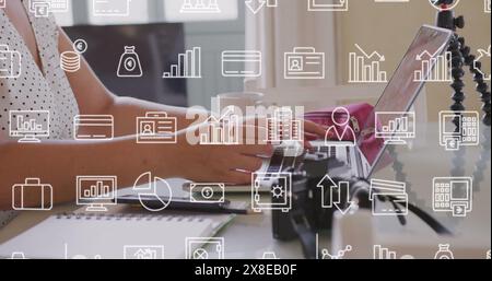 Image of multiple icons over midsection of caucasian woman using laptop Stock Photo
