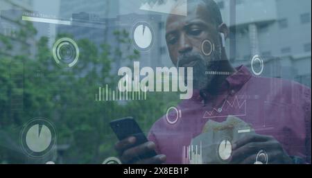 Image of graphs, loading bars, circles, african american man using cellphone and eating burger Stock Photo