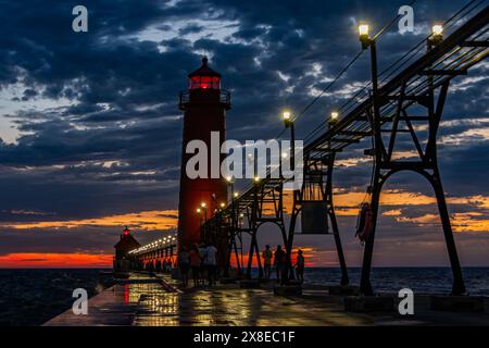 A sunset and storm clouds create dramatic lighting behind Grand Haven, Michigan lighthouse and pier Stock Photo