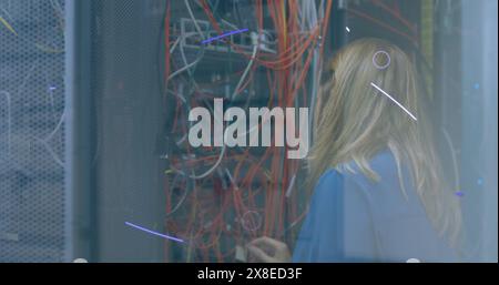 Caucasian woman wearing blue shirt, examining server cables Stock Photo