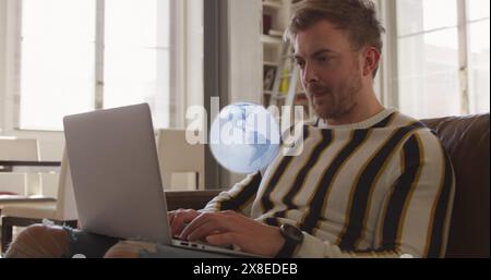 Image of globe spinning over caucasian man using laptop Stock Photo