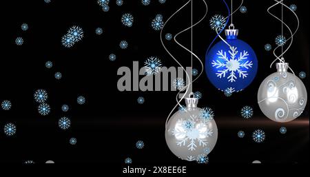 Image of snow flakes falling over hanging bauble decorations and light spot on black background Stock Photo