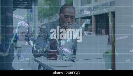 Image of graphs, numbers, senior african american man with laptop eating breakfast in cafes Stock Photo