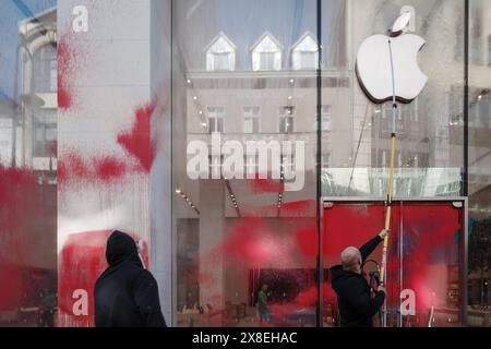 Berlin, Germany - MAY 17, 2024: Workers clean red paint splattered on the glass facade of an Apple store. Stock Photo