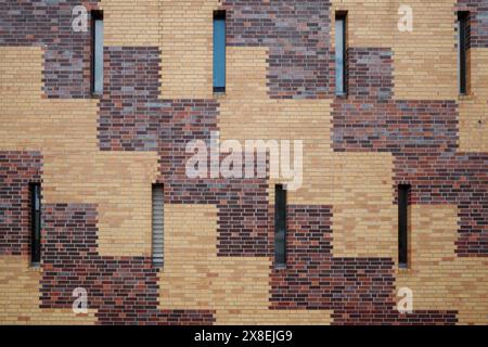 A modern brick wall with an intricate geometric pattern formed by alternating red and yellow bricks. Stock Photo