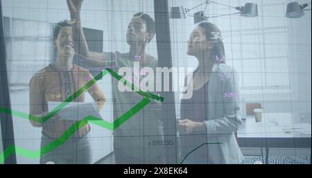 Image of data processing against three diverse women discussing over glass board at office Stock Photo