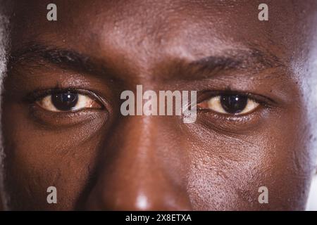 At gym, African American man with intense gaze, close-up of his eyes. Focused and determined in gym environment, showing commitment and strength with Stock Photo