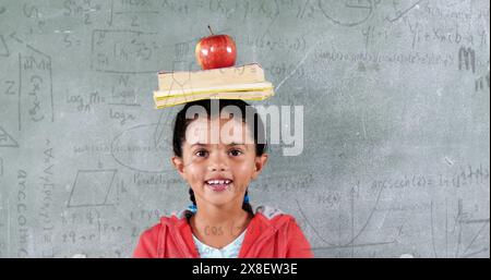 In school, biracial female student is smiling, standing in front of chalkboard Stock Photo