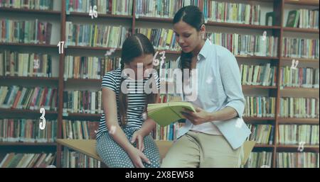 In school library, Hispanic teacher and Caucasian student reading book together Stock Photo