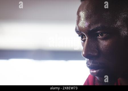 Strong and fit African American man sweating during intense workout at gym, copy space. Gym equipment and bright lights creating focused atmosphere, h Stock Photo