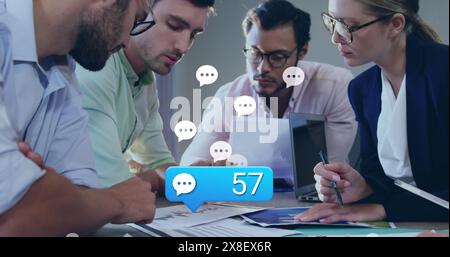 Image of message icons with increasing numbers over diverse colleagues discussing at office Stock Photo