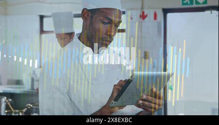 Image of data processing against african american male chef using digital tablet in the kitchen Stock Photo