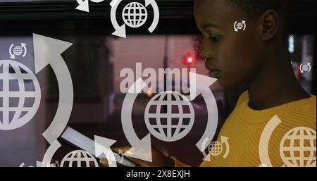 Image of arrows around globes over african american girl using digital tablet in bus Stock Photo