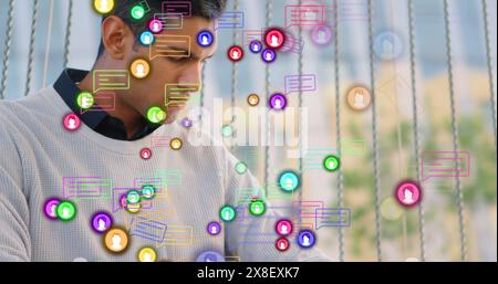 Image of message boxes, profile icons, caucasian man working on laptop and checking smartwatch Stock Photo