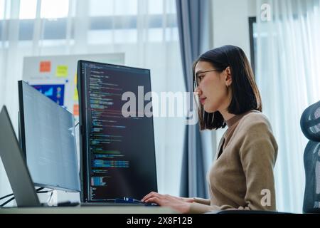 Asian prompt engineer develop coding app with software data sitting in front of computer monitor at office Stock Photo