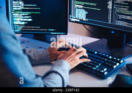 close up hand of Asian prompt engineer develop coding app with software data sitting in front of computer monitor at office Stock Photo