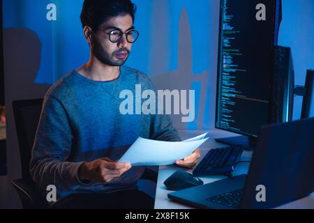 Indian software development working on coding  computer screen and flowchart at night in modern office Stock Photo