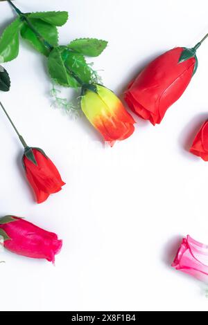 Flowers composition. Multicolored artificial roses flowers tulips on white background with copy space. Top view. Stock Photo