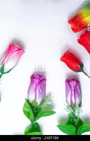 Multicolored artificial roses flowers tulips on white background. Top view Stock Photo