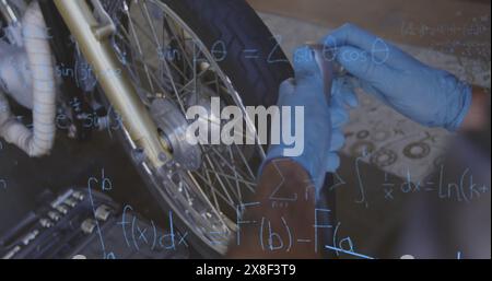 Caucasian male coach wearing blue gloves, fixing bicycle wheel Stock Photo