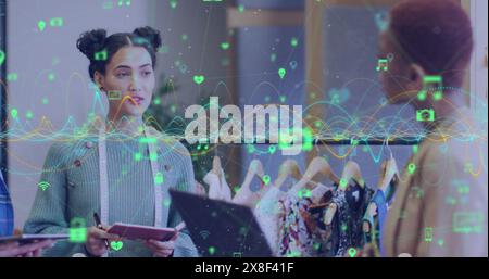 Image of graphs and connected icons over diverse female designers discussing about fashion Stock Photo