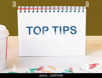 Business concept. Text TOP TIPS on a checkered notebook on the office desk of a manager, banker Stock Photo